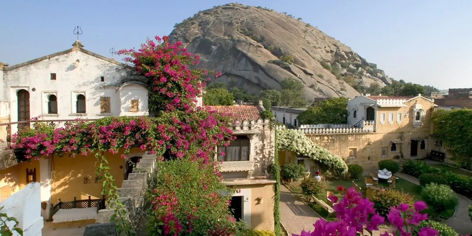 Il Rawla Narlai tra le bouganville in fiore, con la grande collina di granito che sovrasta il villaggio