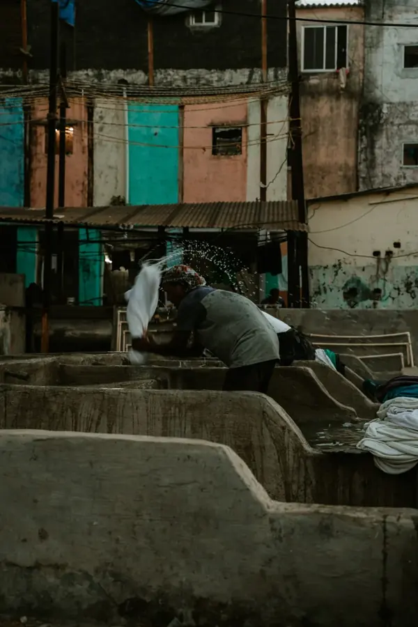 Un lavandaio sbatte i panni in una vasca di cemento del Dhobi Ghat