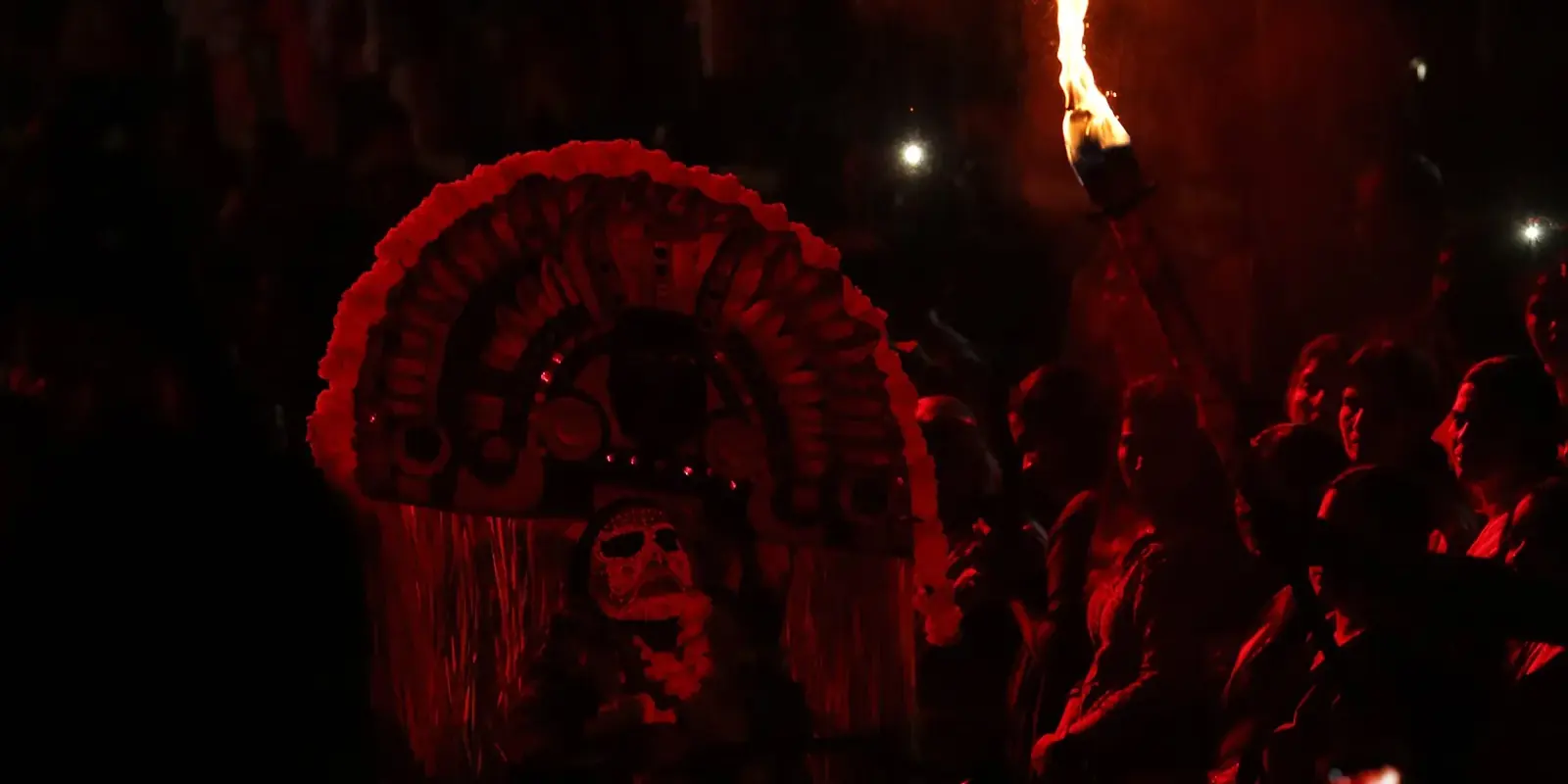 Artista del Mudiyettu con la grande corona rossa della dea Kali, illuminato da una torcia nella notte