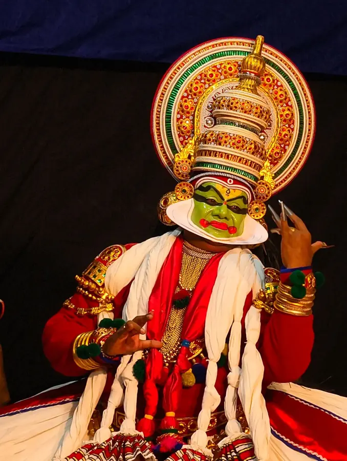 Danzatore di Kathakali con il volto verde, la cornice bianca del chutti e l'alto copricapo dorato
