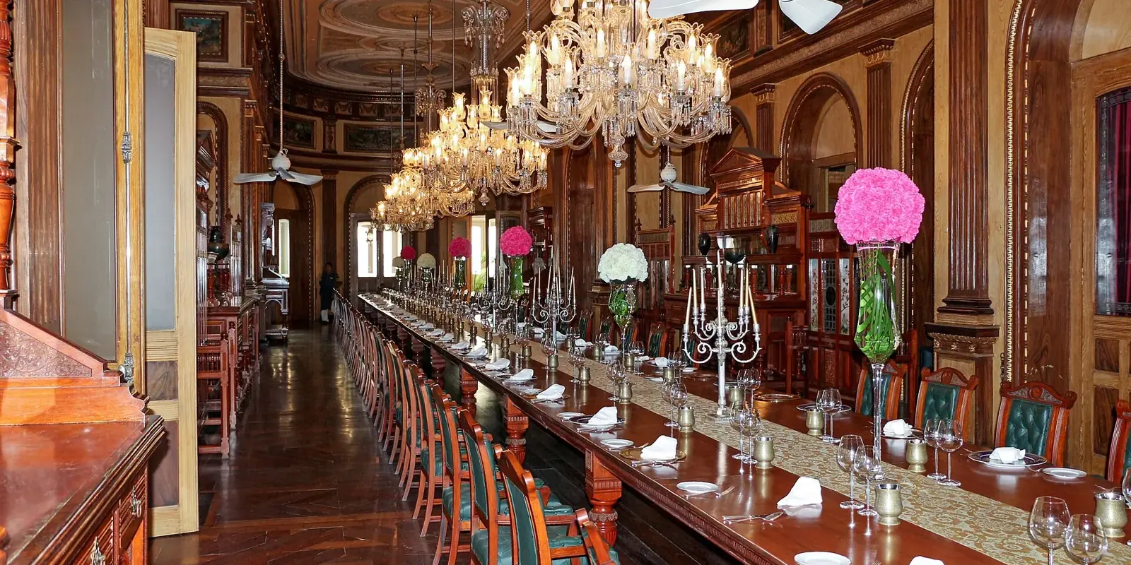 La sala da pranzo del Falaknuma Palace a Hyderabad: un tavolo lunghissimo apparecchiato sotto file di lampadari di cristallo