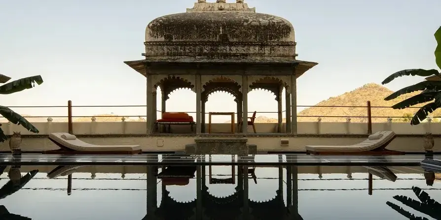 Il padiglione con la cupola sulla terrazza del RAAS Devigarh, riflesso nella piscina, con le colline degli Aravalli