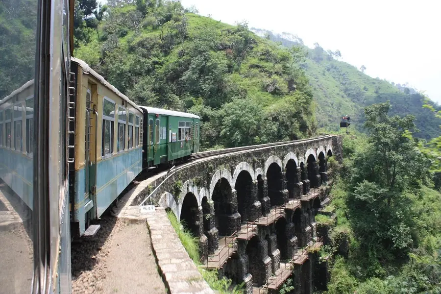 Il treno della Kalka–Shimla su un viadotto di pietra ad arcate sovrapposte, tra colline verdi