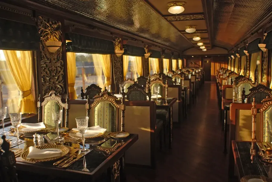 La carrozza ristorante Mayur Mahal del Maharajas' Express con tavoli apparecchiati, sedie intagliate e tende dorate